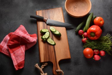 Mutfak tahtasındaki sebzeleri doğramak. Salata hazırlamak ya da pişirmek