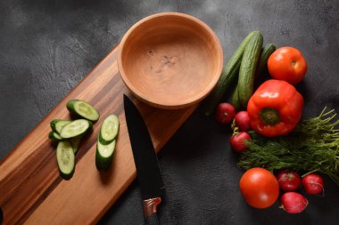 Mutfak tahtasındaki sebzeleri doğramak. Salata hazırlamak ya da pişirmek