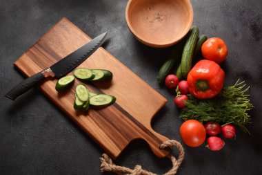 Mutfak tahtasındaki sebzeleri doğramak. Salata hazırlamak ya da pişirmek