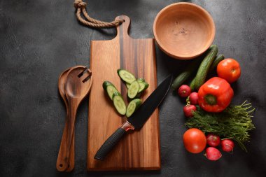 Mutfak tahtasındaki sebzeleri doğramak. Salata hazırlamak ya da pişirmek