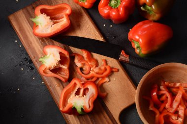 Mutfak tahtasındaki kırmızı biberi bıçakla kesmek. Salata ya da yemek hazırlama. Aşçı ya da aşçı konsepti. Profesyonel mutfak.