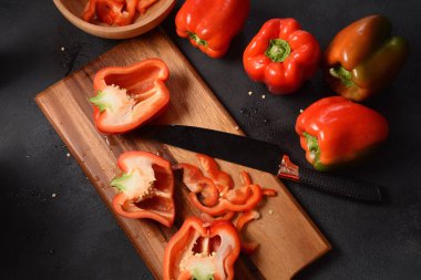 Mutfak tahtasındaki kırmızı biberi bıçakla kesmek. Salata ya da yemek hazırlama. Aşçı ya da aşçı konsepti. Profesyonel mutfak.