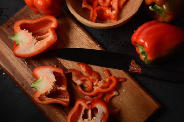 Mutfak tahtasındaki kırmızı biberi bıçakla kesmek. Salata ya da yemek hazırlama. Aşçı ya da aşçı konsepti. Profesyonel mutfak.