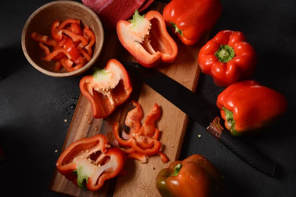 Mutfak tahtasındaki kırmızı biberi bıçakla kesmek. Salata ya da yemek hazırlama. Aşçı ya da aşçı konsepti. Profesyonel mutfak.