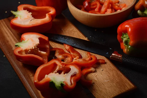 Mutfak tahtasındaki kırmızı biberi bıçakla kesmek. Salata ya da yemek hazırlama. Aşçı ya da aşçı konsepti. Profesyonel mutfak.