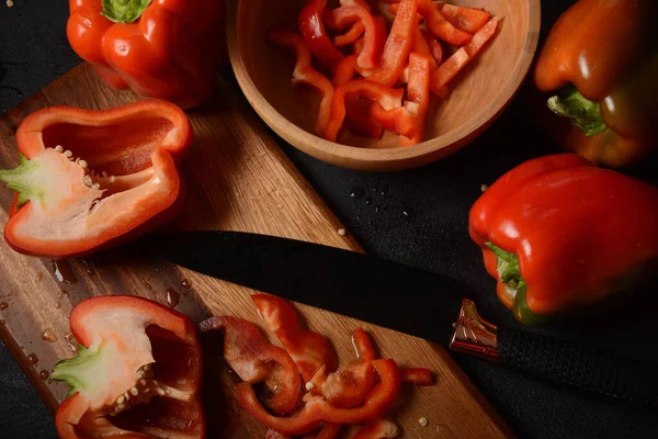 Mutfak tahtasındaki kırmızı biberi bıçakla kesmek. Salata ya da yemek hazırlama. Aşçı ya da aşçı konsepti. Profesyonel mutfak.