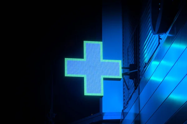 Neon yeşil eczane haçı, Bokeh binasının altında.