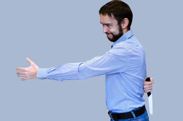 El concepto de negocio de la traición. hombre de negocios extiende su mano para un apretón de manos y sostiene un cuchillo detrás de su espalda — Foto de Stock