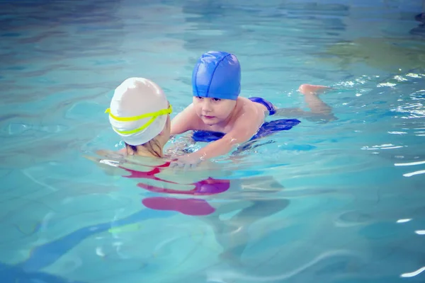 Petit garçon utilisant le kickboard pour apprendre à nager avec un entraîneur dans la piscine — Photo