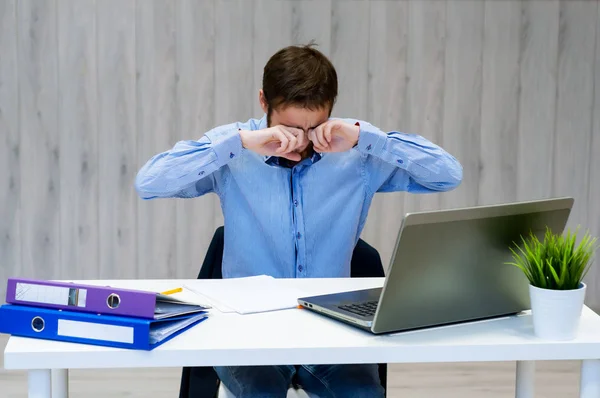 Joven hombre de negocios se frota los ojos y sufre de ojos cansados después de largas horas de uso de la computadora portátil — Foto de Stock