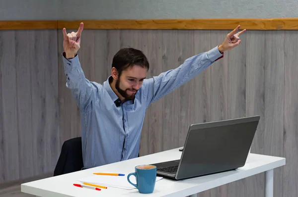 Портрет человека, который смотрит на ноутбук и радостно поднимает руки вверх. Концепция хороших новостей, победы и великих достижений — стоковое фото
