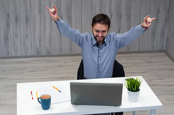Портрет человека, который смотрит на ноутбук и радостно поднимает руки вверх. Концепция хороших новостей, победы и великих достижений — стоковое фото