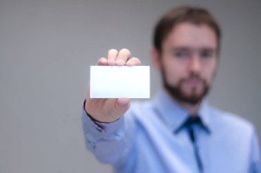 Beyaz iş kartı üzerinde modern ofis tutan genç iş adamı arka plan bulanıklık