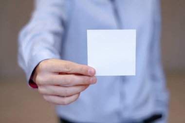 Beyaz iş kartı üzerinde modern ofis tutan genç iş adamı arka plan bulanıklık