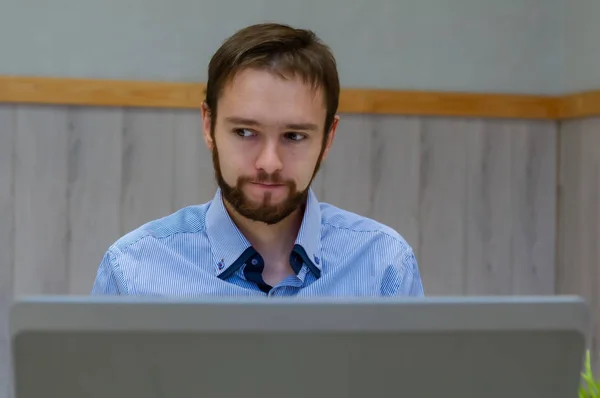Joven hombre de negocios vestido con camisa azul mientras usa el ordenador portátil en la oficina . —  Fotos de Stock