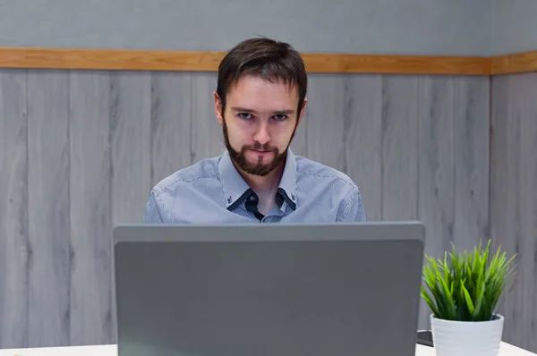 Молодой бизнесмен в синей рубашке во время использования ноутбука в офисе . — стоковое фото