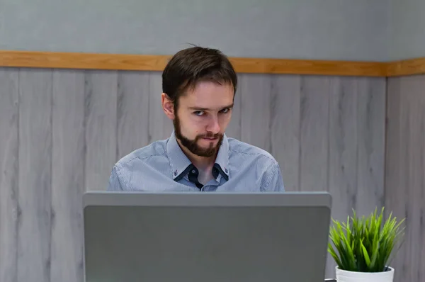 Joven hombre de negocios vestido con camisa azul mientras usa el ordenador portátil en la oficina . —  Fotos de Stock