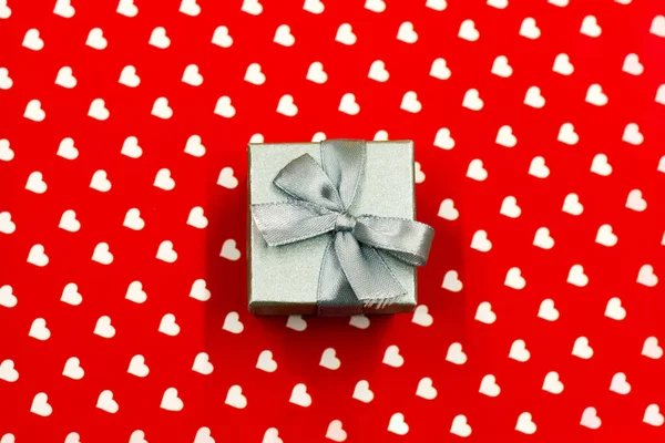 Malá šedá dárková krabice na bílém a červeném pozadí srdce. Valentýn, svatba, láska, koncept štěstí — Stock fotografie