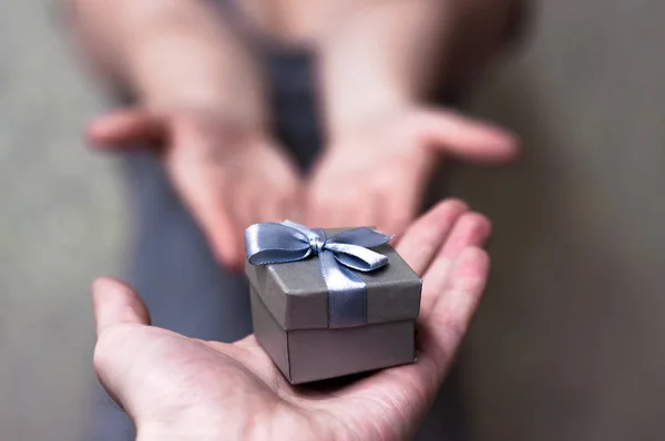 Close Up auf Händen Mann gibt eine kleine graue Geschenkbox für Frau zum Geburtstag, Weihnachten und Neujahr, Hochzeit, Valentinstag — Stockfoto