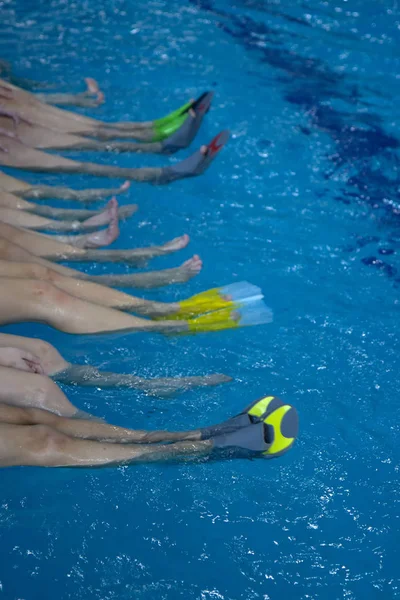 Small children sitting on edge of swimming pool and chatting with their feet in the blue warm water, Side view — 스톡 사진