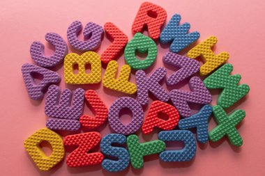 Pembe arka planda renkli plastik alfabe harfleri, üst görünüm
