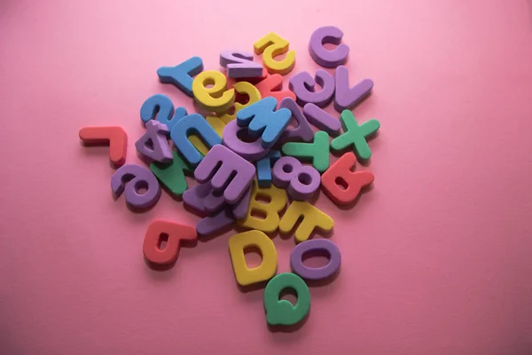 ピンクの背景にカラフルなプラスチック製のアルファベット文字、トップビュー — ストック写真