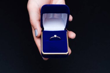 Elinde nişan yüzüğü olan mavi bir kutu tutan bir kadın. Evlenme teklif eden bir kadın