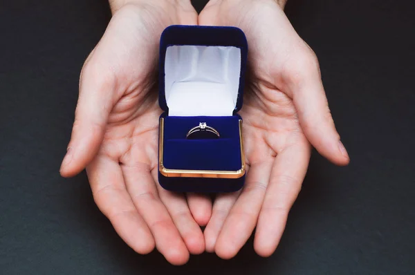 사람들은 약혼 반지가 달린 파란 상자를 들고 손을 잡는다 — 스톡 사진