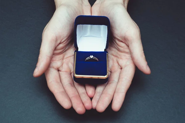 사람들은 약혼 반지가 달린 파란 상자를 들고 손을 잡는다 — 스톡 사진
