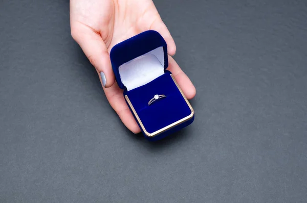여자가 약혼 반지가 달린 파란 상자를 들고 손을 잡고 있습니다. 한 여자가 결혼 신청을 하는 모습 — 스톡 사진