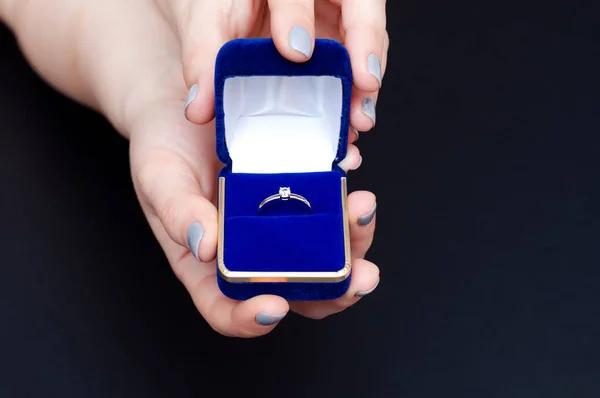Kvinna hand håller en blå låda med en förlovningsring. Förslag från en kvinna som vill gifta sig — Stockfoto