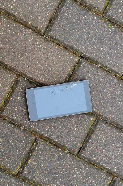 Telefone com tela quebrada no asfalto. Alguém deixou cair o dispositivo . — Fotografia de Stock