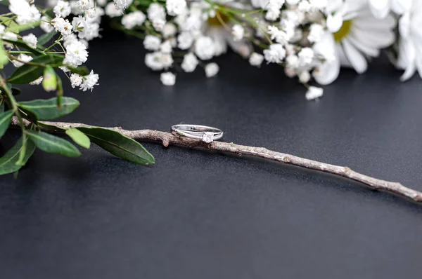 Bröllop ring sitter på en trädgren med vita blommor på en svart bakgrund — Stockfoto