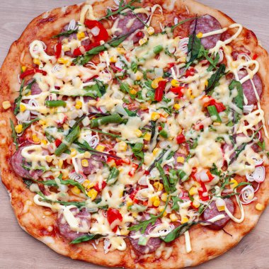 Tahta arka planda pizza, üst manzara. Margarita, roka, deniz ürünleri, sosis, sebze, mısır, peynir.