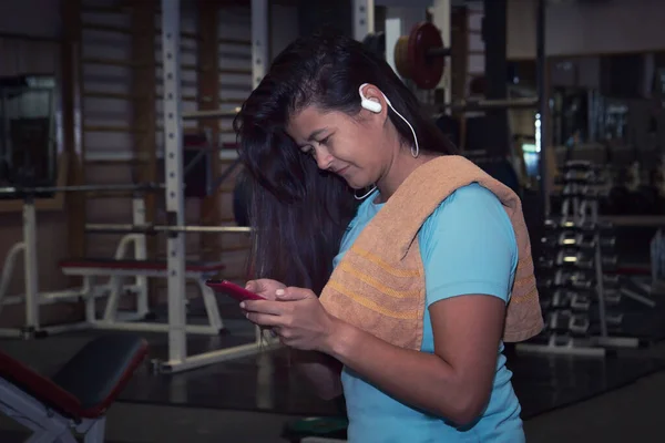 Active girl with smartphone listening to music in gym