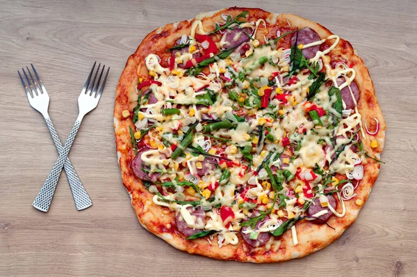 Hot homemade pizza with cutlery fork and knife on wooden background.