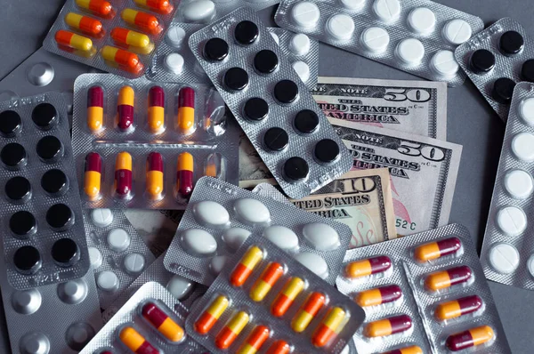 Medical pills in money background as a symbol of health care costs.