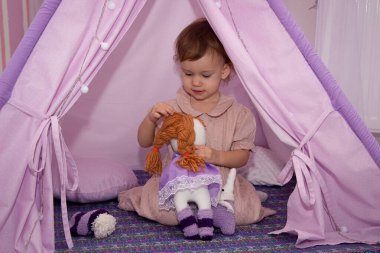 2 yaşındaki küçük kız çocuk odasında oyuncak arabasıyla ya da çadırda oynuyor.