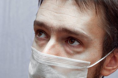 Tıbbi maskeli hasta bir adam. Hüzünlü gözler kapat