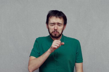 Adam eline öksürürken komik bir ifade takınıyor.