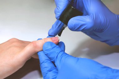 Manikür uzmanı tırnak altlarını pürüzsüz bir cilayla kaplıyor. Kapat.