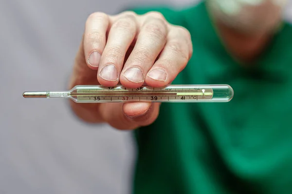 Man with mercury thermometer with a high temperature in hand. close up