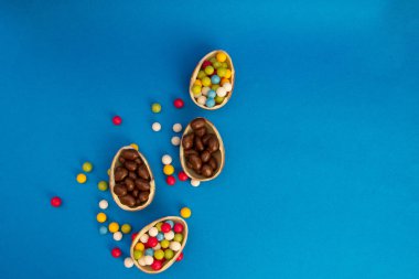 Çikolatalı paskalya yumurtaları mavi arka planda şekerle çatlamış ve kopyalanmış.