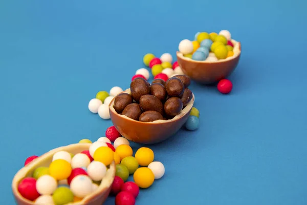 Deliciosos Ovos Páscoa Chocolate Quebrado Espalhar Doces Coloridos Fundo Azul — Fotografia de Stock