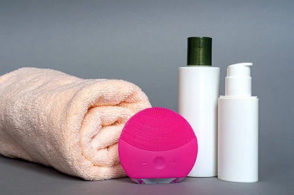 set of cosmetics for face care with a towel on a gray background