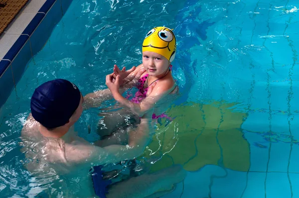 Swimming pool coach teaches a little girl to swim. water activity