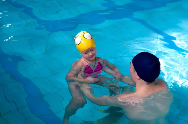 Swimming pool coach teaches a little girl to swim. water activity