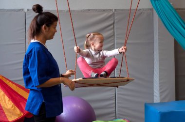 Salıncakta salıncakta sallanan duyusal terapiden zevk alan gülümseyen bir kız.