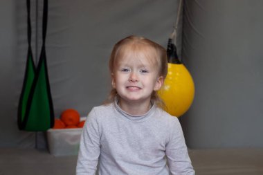 Gülümseyen kız spor salonunda arka planda duyusal bütünleşmede oturuyor.