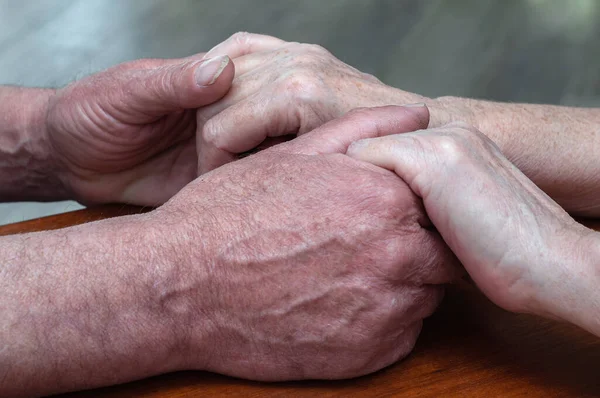 Yaşlı bir ailenin eski ellerini tutması. Yakın görüş, psikolojik destek konsepti, mutlu evliliğe güven.